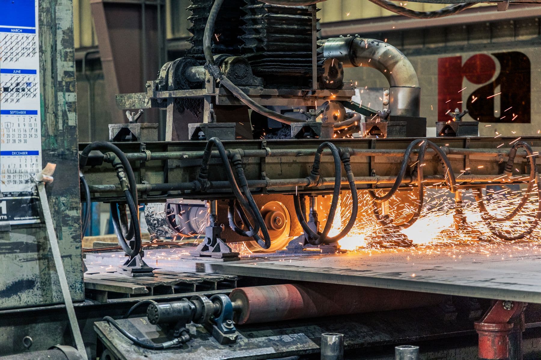 Precision cutting machinery working a metal plate, with bright sparks at the cutting head