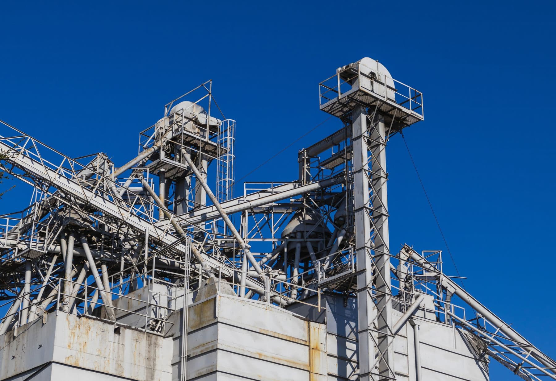 Steel processing structures, conveyors and pipes against a clear blue sky