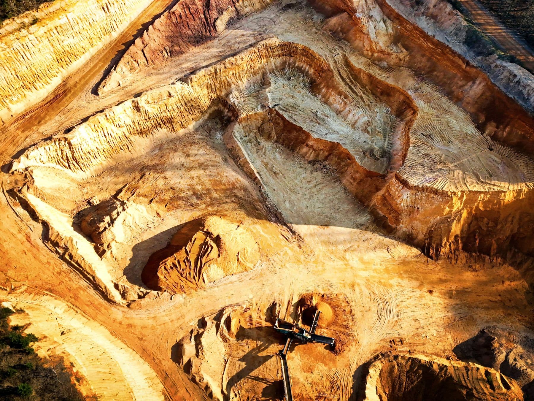 Aerial view of terraced earth and excavation equipment in an open-pit mine